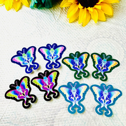 Colorful moth-shaped stickers on a textured white surface with sunflowers in the background.